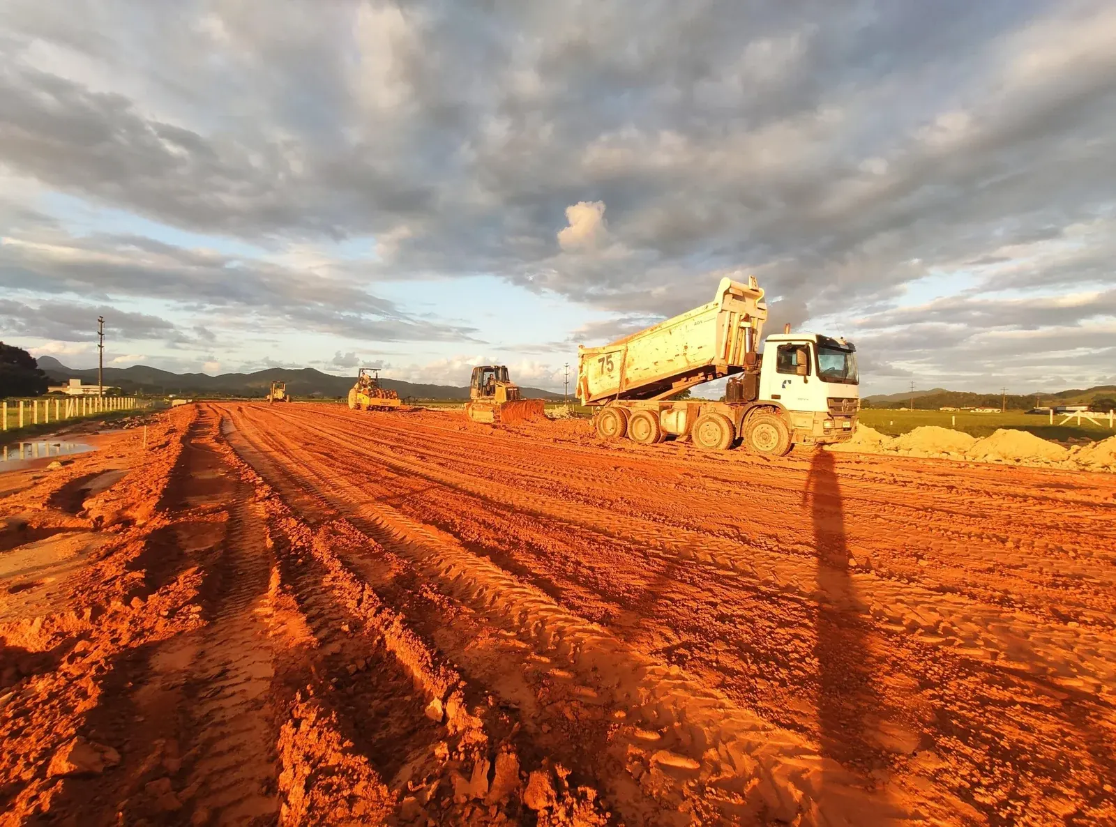 Terraplenagem em execução, com caminhão basculante sobre o aterro